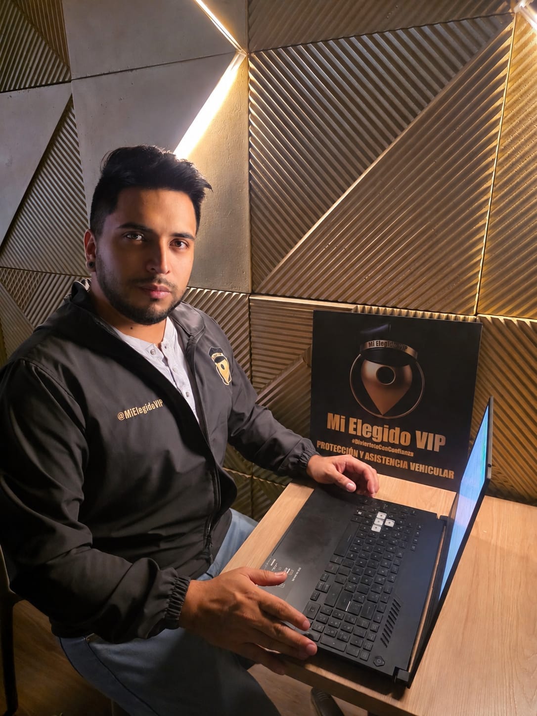 Coordinador del servicio de conductor elegido de Mi Elegido VIP junto a un computador portátil y al distintivo de la empresa